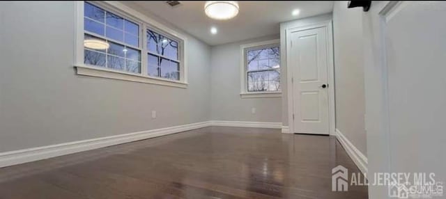 spare room with baseboards and wood finished floors