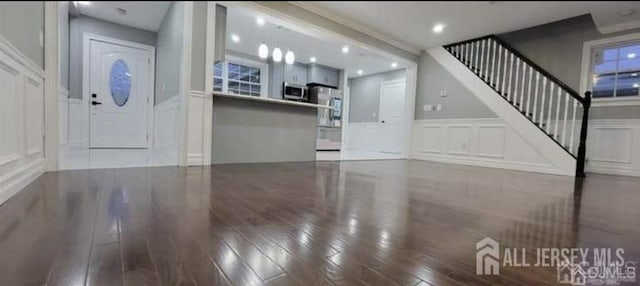 foyer featuring wood-type flooring, stairs, a decorative wall, and a wainscoted wall