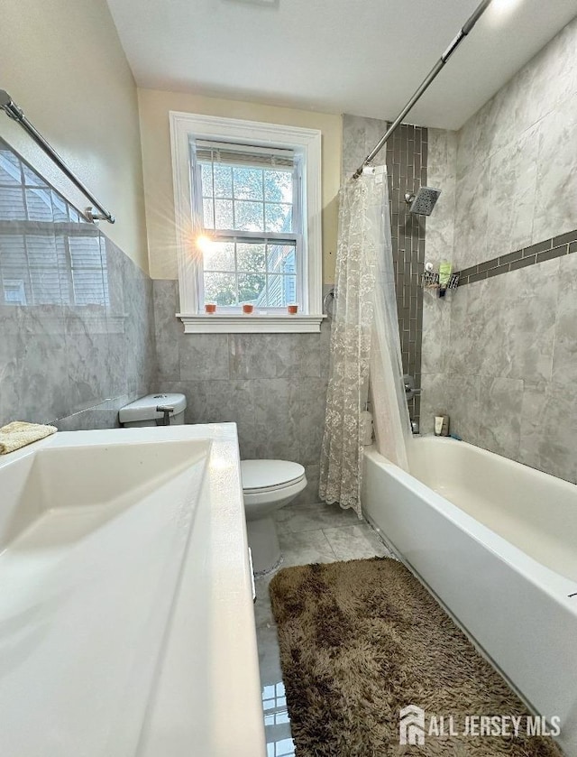 bathroom with vanity, toilet, shower / bathtub combination with curtain, a wainscoted wall, and tile walls
