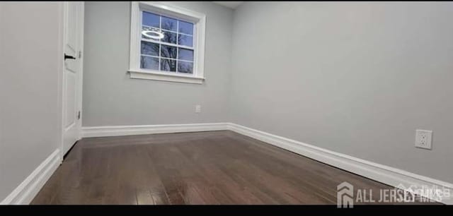 empty room featuring baseboards and dark wood-style floors