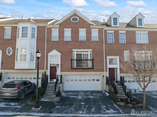 view of property featuring brick siding, a garage, and driveway