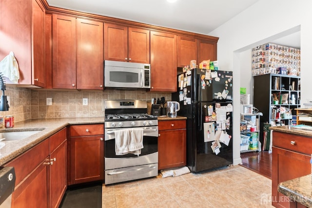 kitchen with light tile patterned floors, light stone countertops, brown cabinets, decorative backsplash, and stainless steel appliances