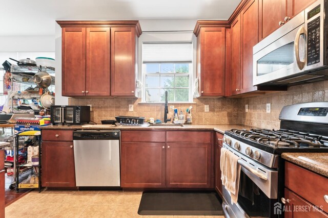 kitchen with stainless steel appliances, a sink, and backsplash