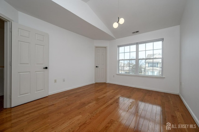 unfurnished room featuring visible vents, light wood-style flooring, baseboards, and lofted ceiling