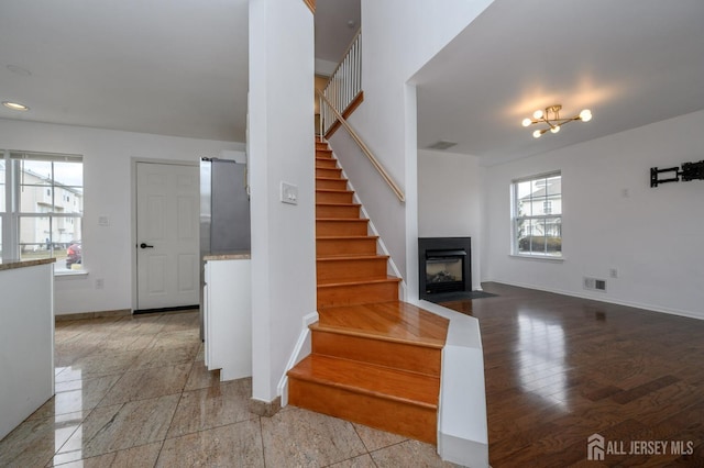 stairway featuring baseboards, a fireplace with flush hearth, and visible vents