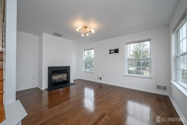 unfurnished living room featuring visible vents, dark wood-type flooring, and a fireplace with flush hearth