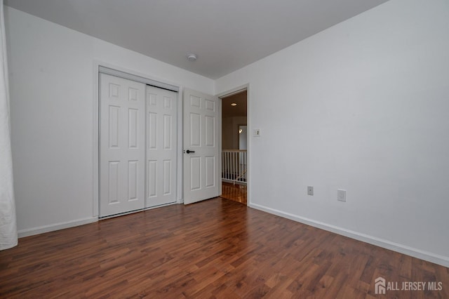 unfurnished bedroom with a closet, baseboards, and wood finished floors