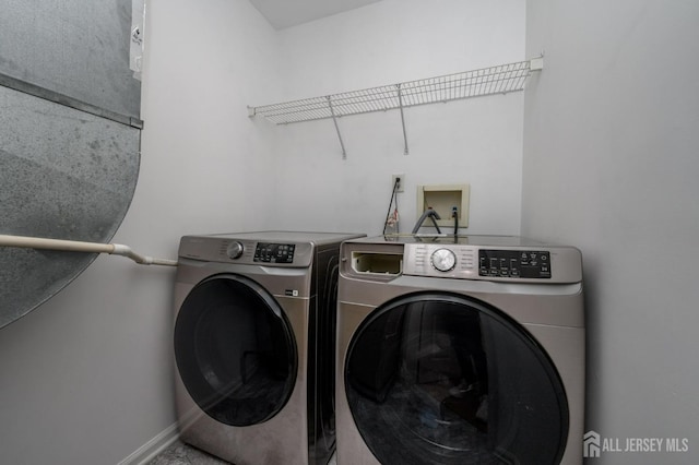 washroom featuring washer and dryer, laundry area, and baseboards