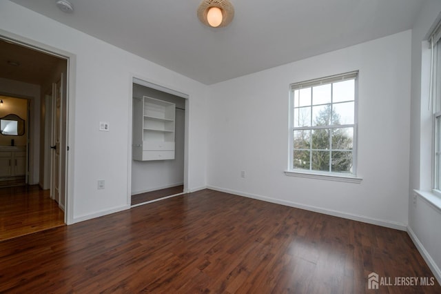 unfurnished room featuring dark wood-type flooring and baseboards