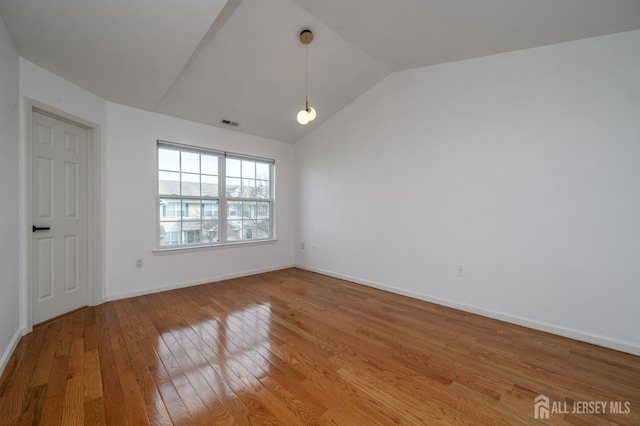 unfurnished room with vaulted ceiling, light wood-style flooring, baseboards, and visible vents