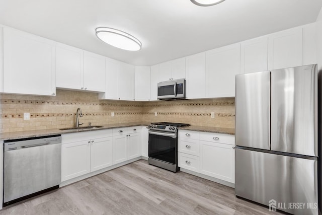 kitchen with stainless steel appliances, light stone countertops, sink, and white cabinets