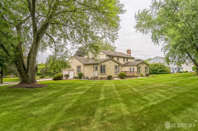 14 Greensview Dr, Scotch Plains, NJ 07076 - view of front facade featuring stucco siding, a chimney, a front yard, a garage, and a deck