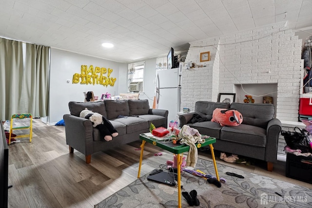 living area with brick wall, cooling unit, and wood finished floors