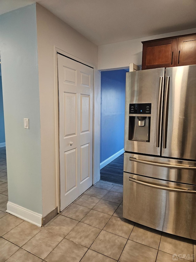 kitchen with light tile patterned flooring, baseboards, and stainless steel fridge with ice dispenser