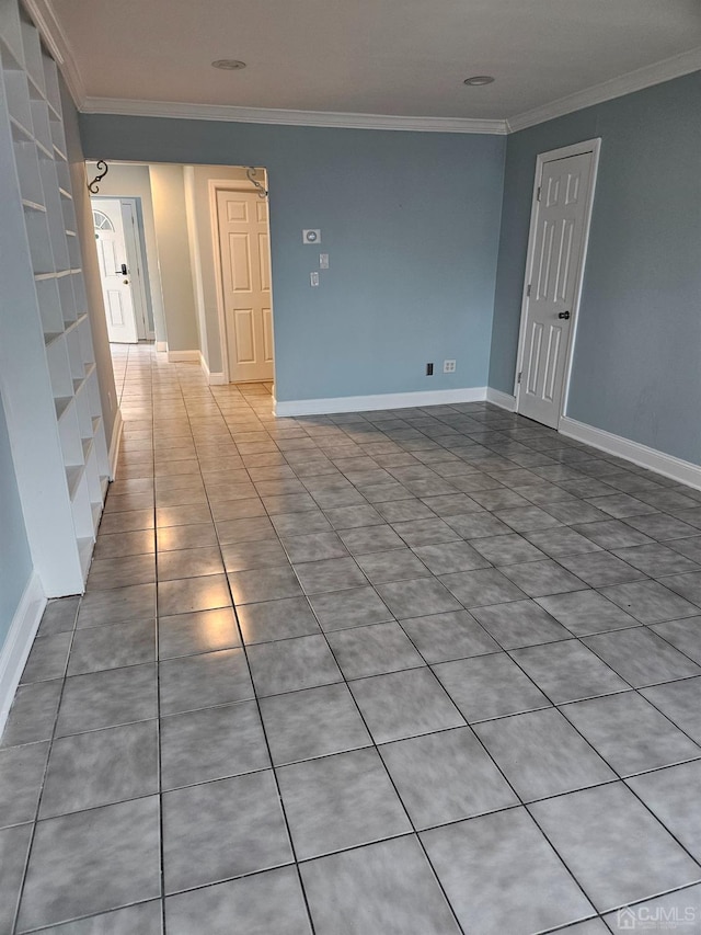 tiled empty room with baseboards and crown molding