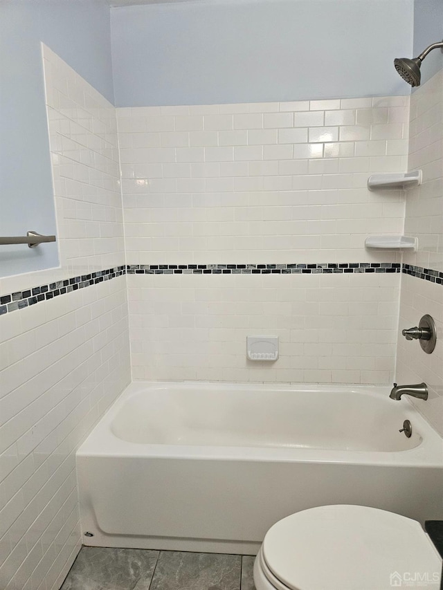 bathroom featuring tile patterned flooring, shower / washtub combination, toilet, and tile walls