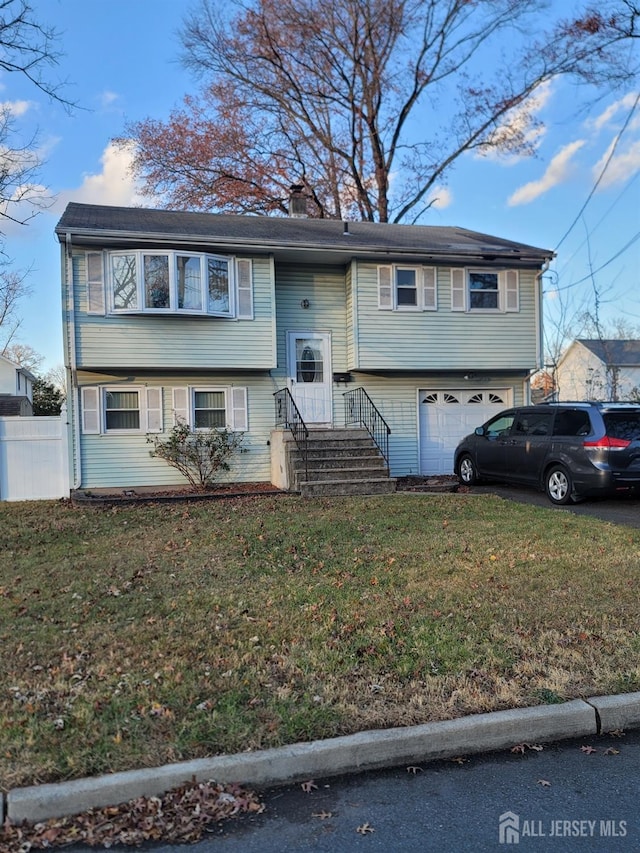 bi-level home featuring a garage, a front yard, a chimney, and fence