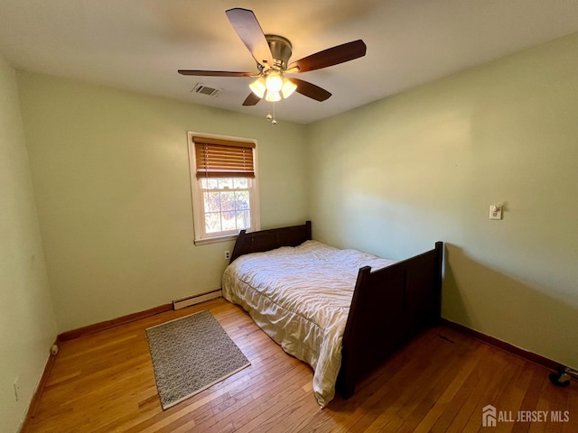 bedroom featuring hardwood / wood-style floors, baseboards, visible vents, and a baseboard radiator