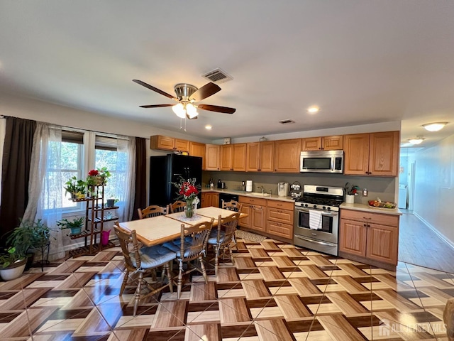 kitchen featuring visible vents, black appliances, a ceiling fan, light countertops, and baseboards