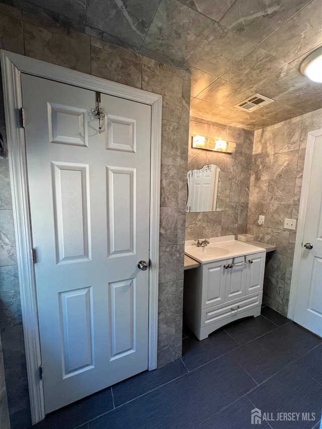 bathroom featuring visible vents, tile walls, and vanity