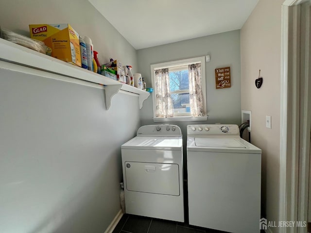 laundry area with washer and dryer, dark tile patterned floors, and baseboards