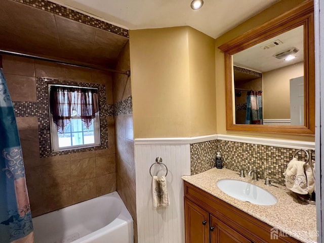 bathroom featuring shower / tub combo, vanity, and a wainscoted wall