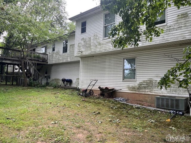 rear view of property featuring cooling unit, a deck, and a lawn