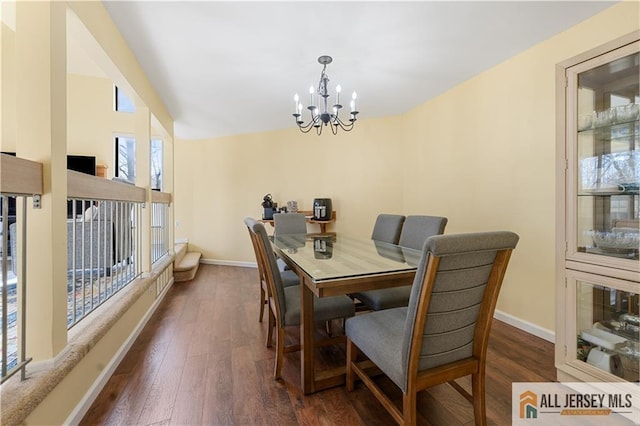 dining space featuring vaulted ceiling, dark wood-type flooring, and an inviting chandelier