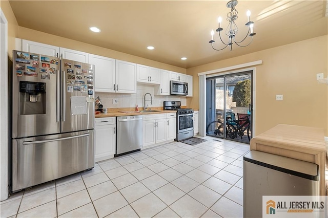 kitchen with sink, tasteful backsplash, light tile patterned floors, appliances with stainless steel finishes, and white cabinets