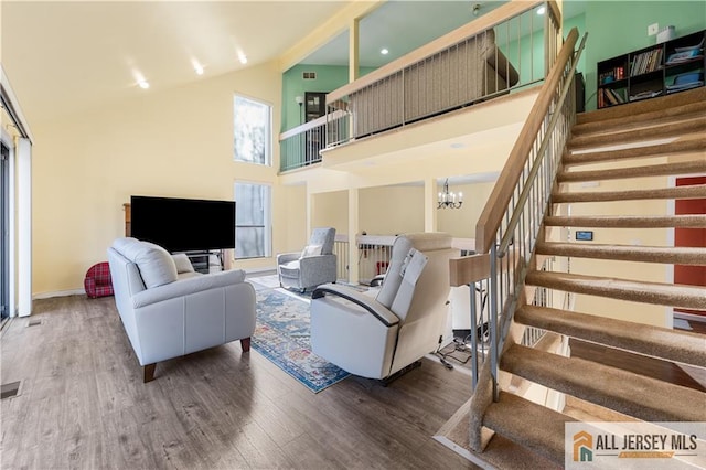 living room featuring hardwood / wood-style flooring, high vaulted ceiling, and a notable chandelier