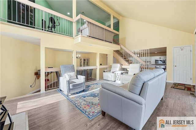 living room with an inviting chandelier, hardwood / wood-style floors, and high vaulted ceiling