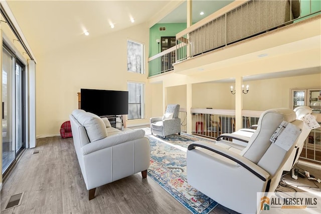 living room featuring plenty of natural light, light hardwood / wood-style floors, and high vaulted ceiling