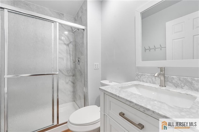 bathroom with vanity, a shower with door, and toilet