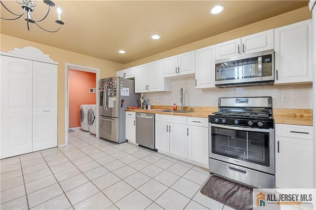 kitchen with appliances with stainless steel finishes, sink, white cabinets, and independent washer and dryer