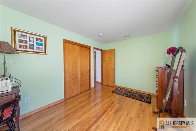 bedroom with light wood-type flooring, baseboards, and visible vents