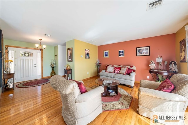 living room featuring a notable chandelier, visible vents, and wood finished floors