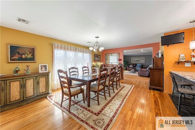 dining room featuring a chandelier, light wood-style floors, and visible vents