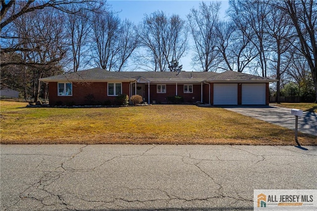 ranch-style home with a garage, aphalt driveway, brick siding, and a front lawn