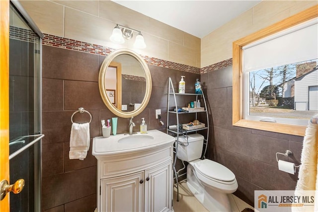 bathroom featuring toilet, tile walls, a shower stall, and vanity