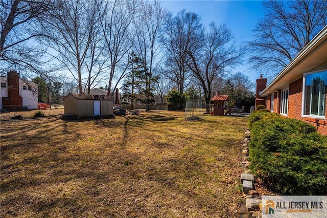 view of yard with a storage shed, fence, and an outbuilding