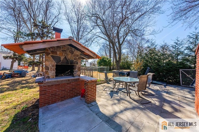 view of patio / terrace featuring outdoor dining space, fence, and an outdoor stone fireplace