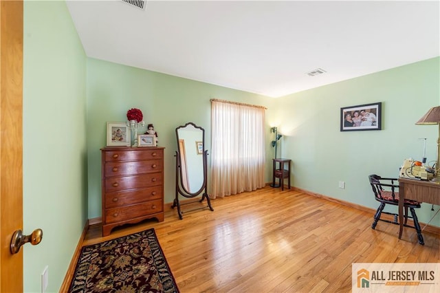 living area featuring visible vents, baseboards, and wood finished floors
