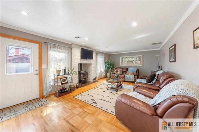 living area featuring ornamental molding, visible vents, and a wood stove