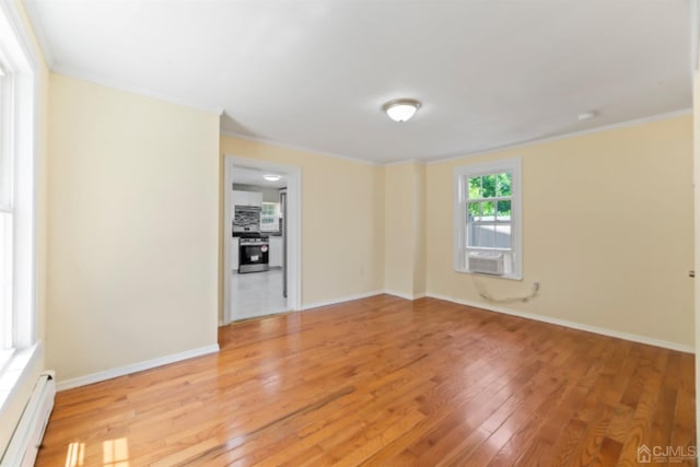 unfurnished room with a baseboard heating unit, crown molding, baseboards, and light wood-style floors