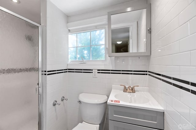 bathroom with toilet, tile walls, a shower stall, and vanity