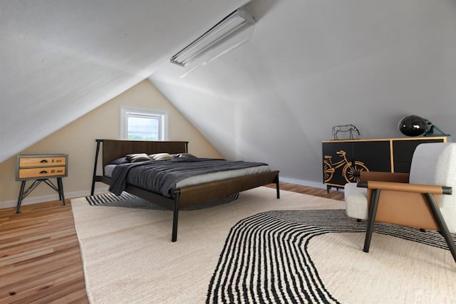 bedroom featuring lofted ceiling, wood finished floors, and baseboards