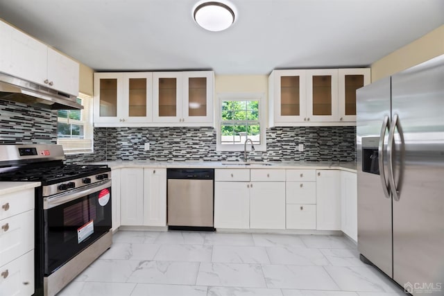 kitchen with under cabinet range hood, appliances with stainless steel finishes, marble finish floor, light countertops, and a sink
