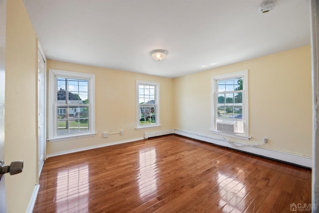 empty room featuring cooling unit, baseboards, wood finished floors, and a baseboard radiator