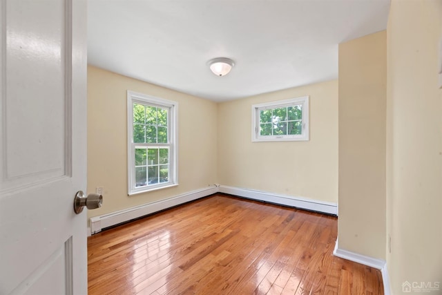 spare room with plenty of natural light, light wood finished floors, baseboard heating, and baseboards