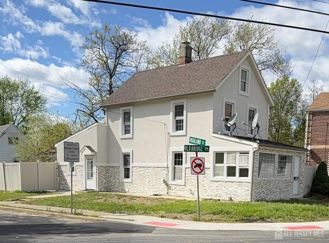 view of front of property with a chimney, fence, stucco siding, and stone siding